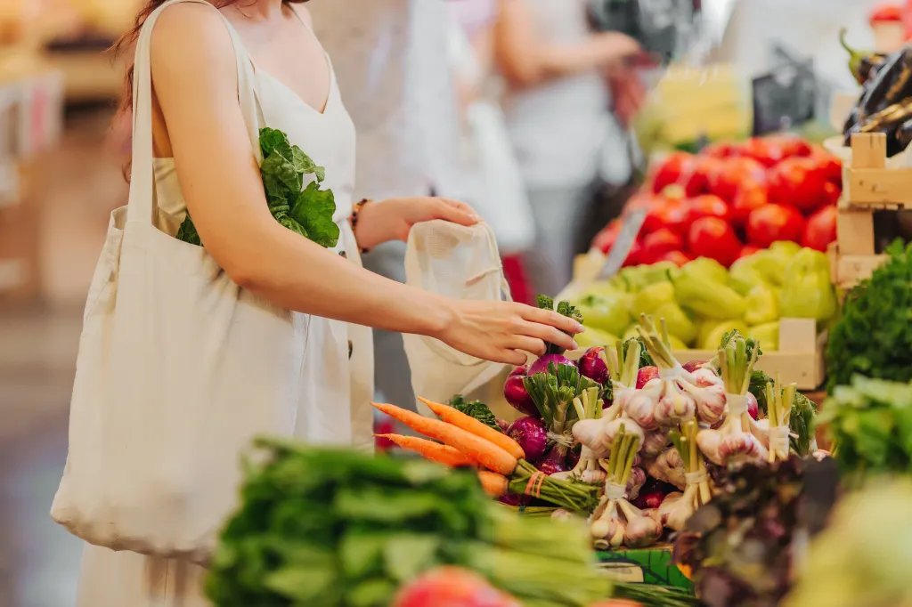A woman puts vegetables into cotton produce bags at a food market