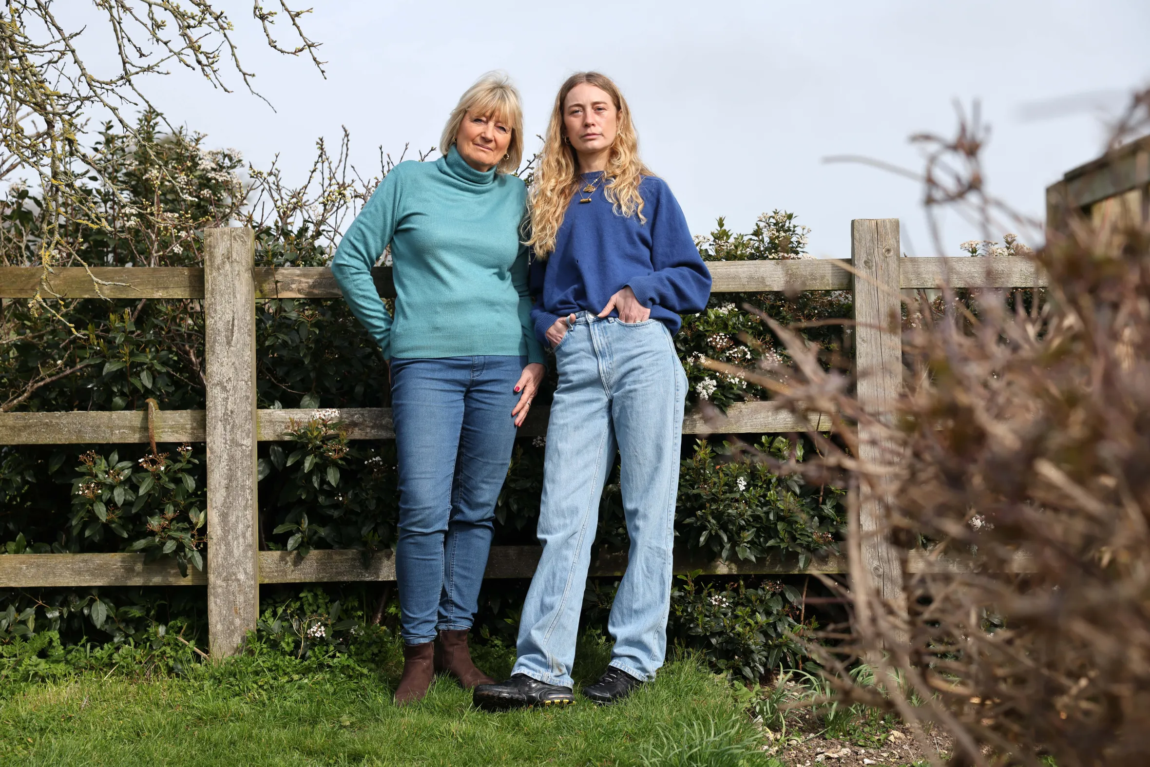 Tricia and Lara Monro, standing in the garden with a fence behind them.