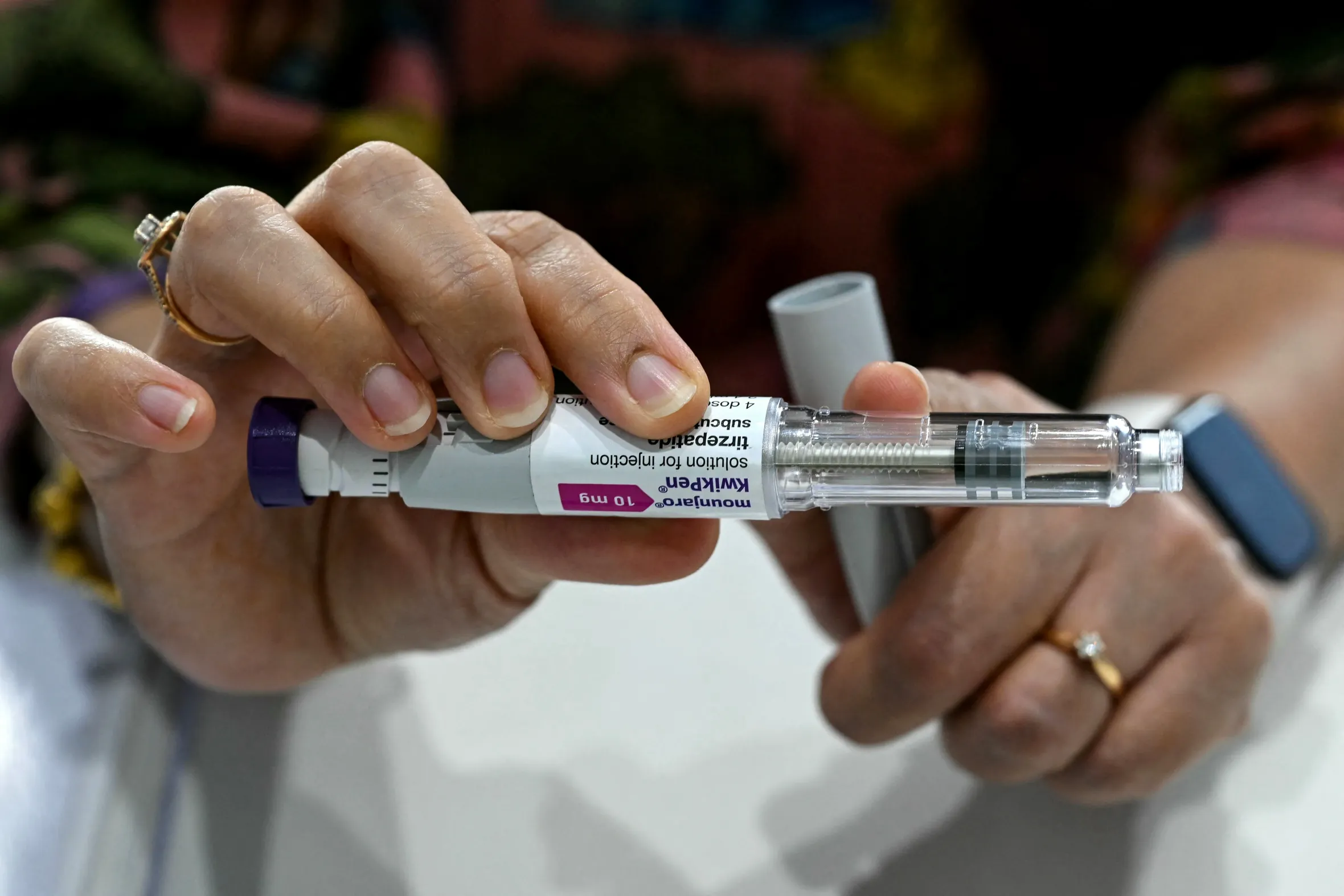 A close-up of a person holding a Mounjaro KwikPen self-injector.