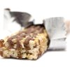 This photo shows a granola bar with the wrapper open and partially pulled back. It lies on a white surface and against a white background.