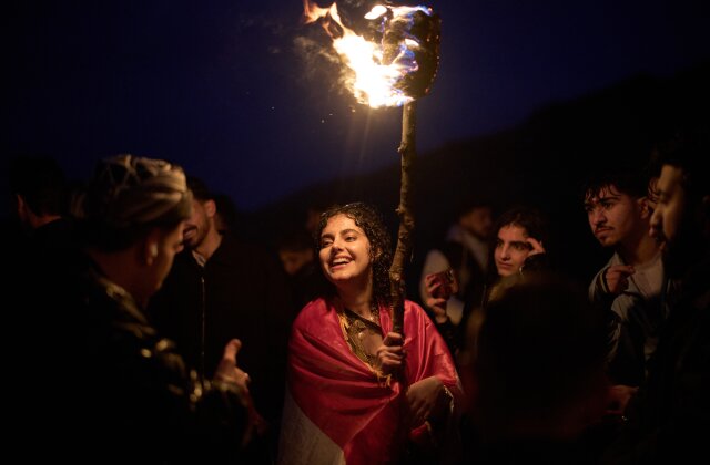 Kurdish women in traditional dress hold lit torches during Nowruz, the Persian New Year, on a hill overlooking the city of Akra in Iraq's autonomous Kurdistan Region, Friday, March 20, 2026. (AP Photo/Leo Correa)