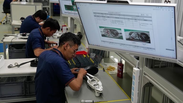 Workers assemble robotic leg components.