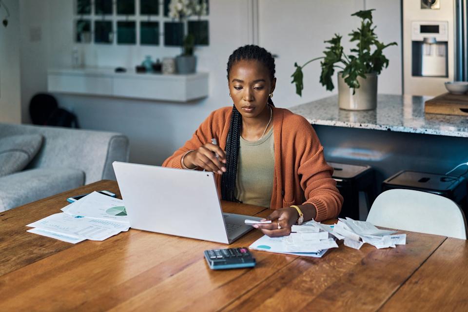 Analyst working with laptop and calculator in home office.