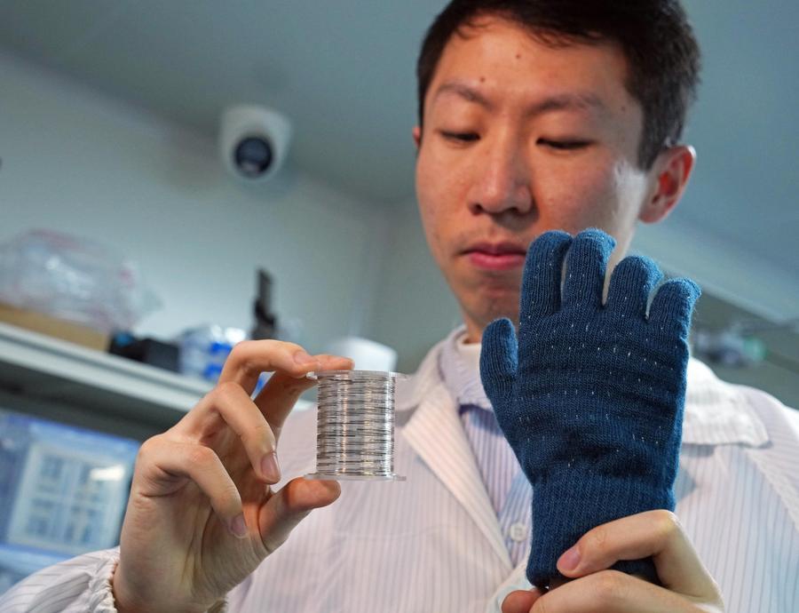 A researcher demonstrates a smart touch glove with rolled fiber chips by weaving the chips at Fudan University in Shanghai, east China, January 19, 2026. (Xinhua/Liu Ying)
